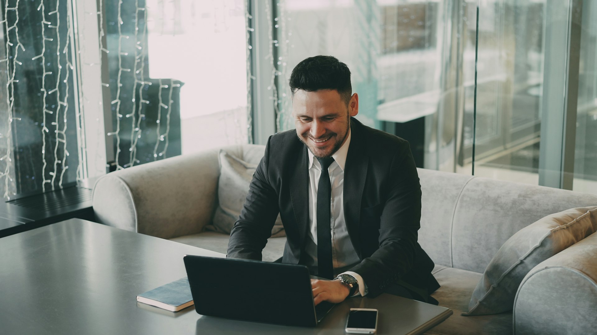 A business owner in a suit smiling at his laptop